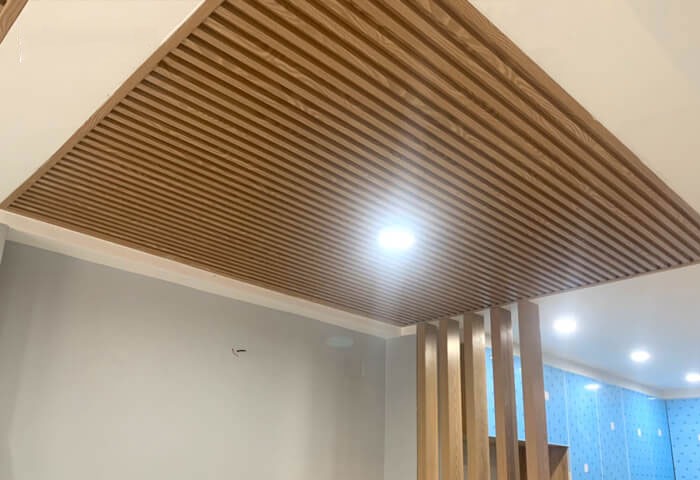 mau-tran-nhua-giat-cap-lam-song-dep-mat4 Trần nhà gỗ xếp dọc với đèn LED chiếu sáng hiện đại trong không gian nội thất tối giản.