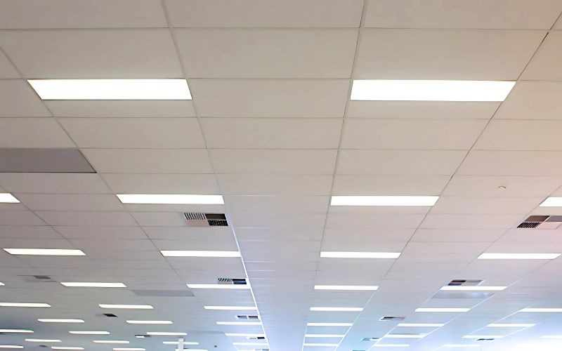 Trần nhà văn phòng hiện đại với lớp gạch vuông và đèn huỳnh quang sáng.