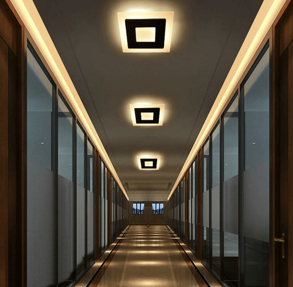Hành lang hiện đại với đèn trần hình vuông, ánh sáng ấm áp, cửa kính hai bên.