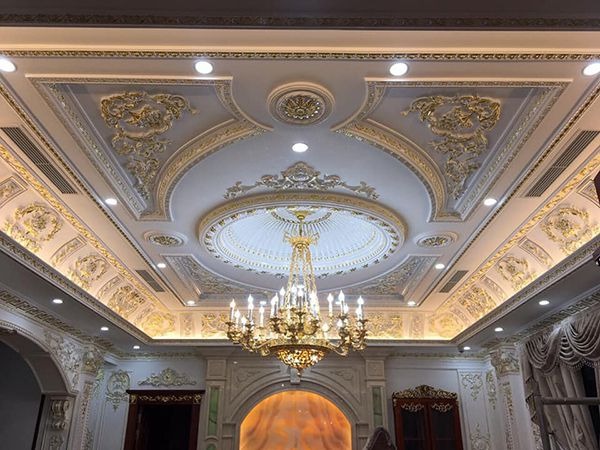 Trần nhà trang trí hoa văn cổ điển với đèn chùm sang trọng trong phòng khách lộng lẫy.