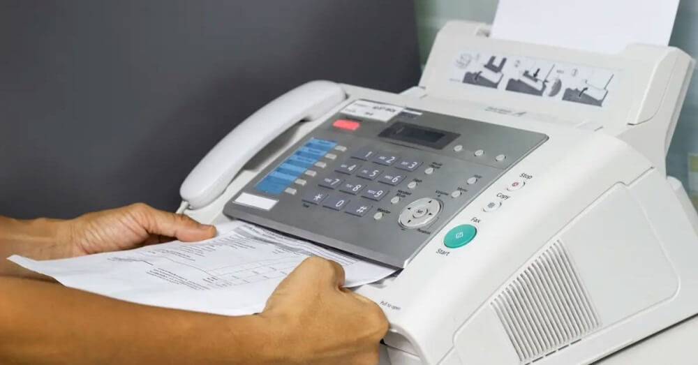 may-fax Người sử dụng máy fax cầm tài liệu, máy fax văn phòng hiện đại, cách gửi fax tại nơi làm việc.