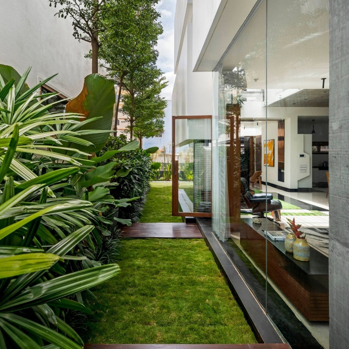 mot-hang-cay-xanh-chay-doc-theo-ben-hong-nha-7 Lối đi xanh mát bên ngoài ngôi nhà kính hiện đại, cây cối trang trí tạo không gian gần gũi với thiên nhiên.