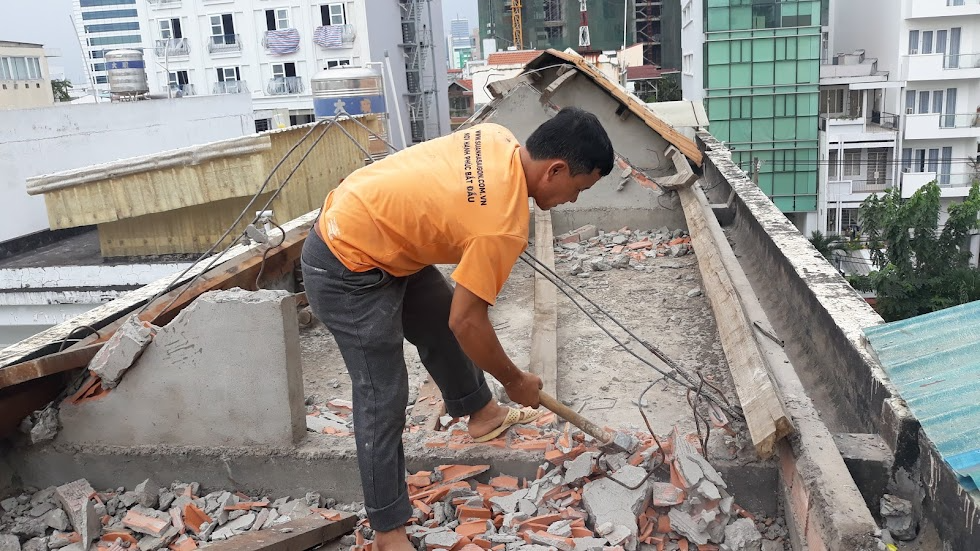 muc-xu-phat-khi-sua-nha-cap-4-khong-co-giay-phep Người đàn ông đập phá gạch trên mái nhà, xung quanh là các tòa nhà cao tầng.