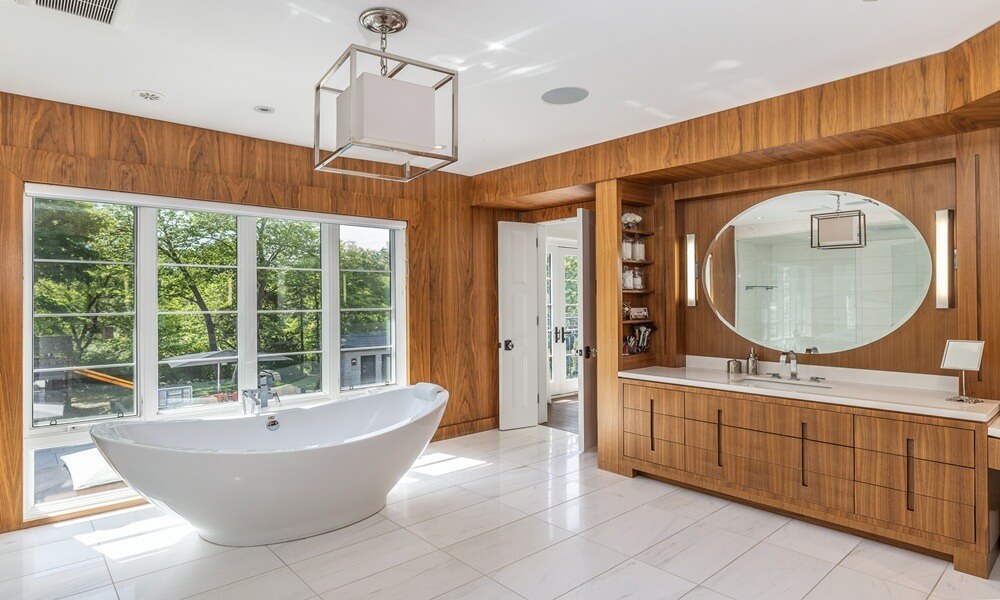 Phòng tắm hiện đại với bồn tắm đứng tự do, gương lớn hình oval và tủ gỗ tự nhiên.