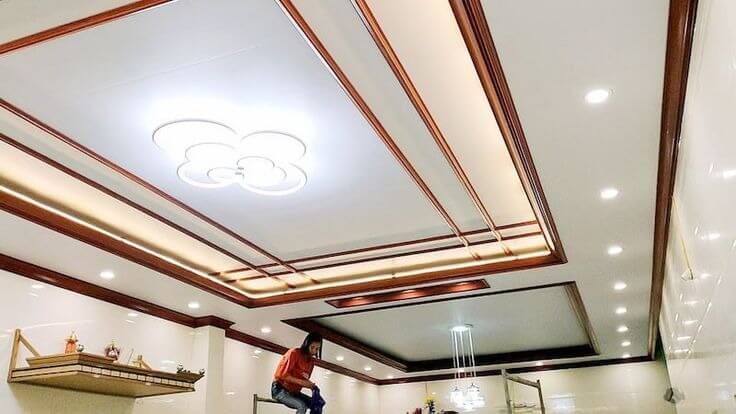 nen-lap-tran-nhua-giat-cap-hay-khong Trần nhà hiện đại với đèn LED trang trí, người thợ sửa chữa trên cao trong phòng sáng sủa.