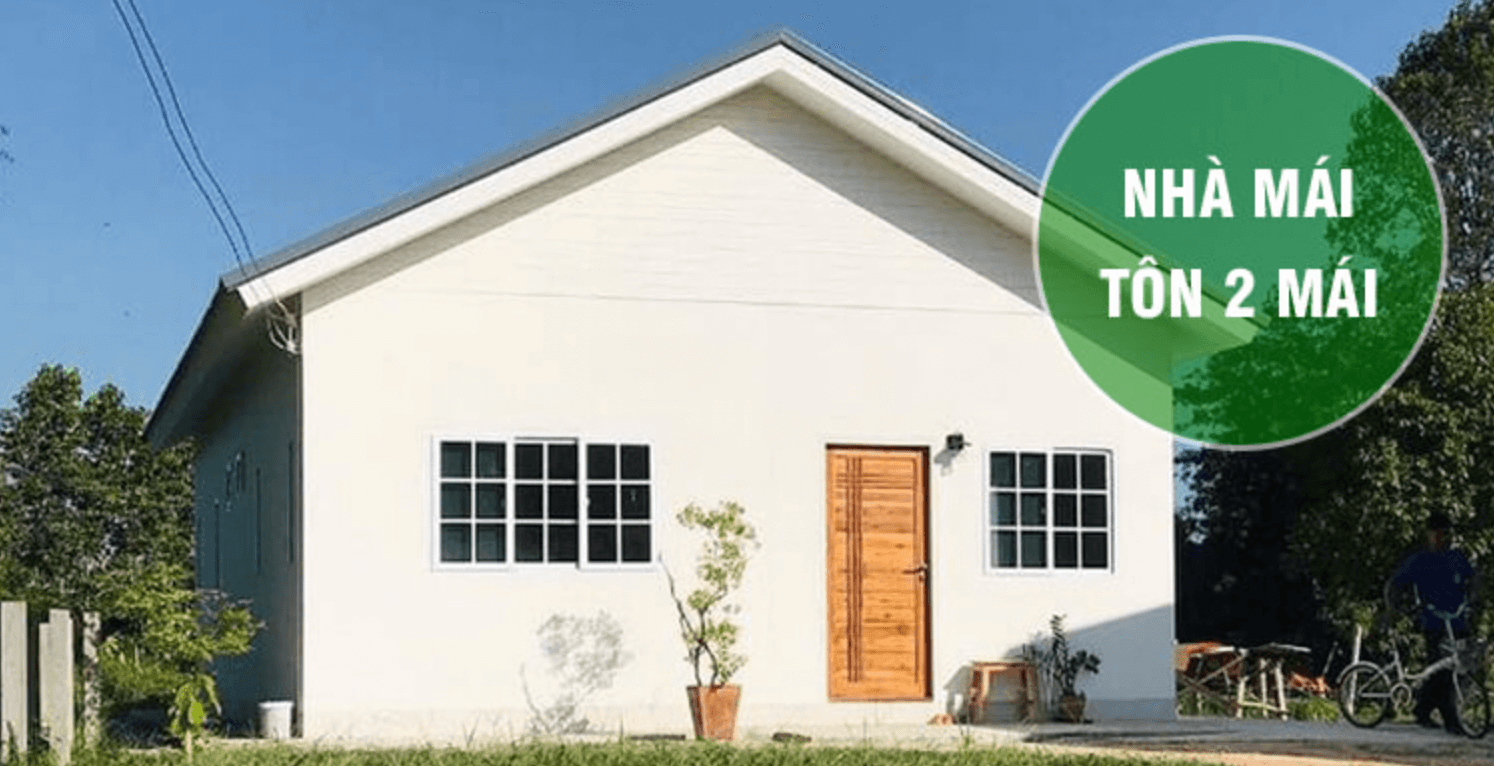 Nhà mái tôn 2 mái màu trắng, cửa gỗ, cửa sổ kính, cây xanh xung quanh, thiết kế đơn giản và hiện đại.
