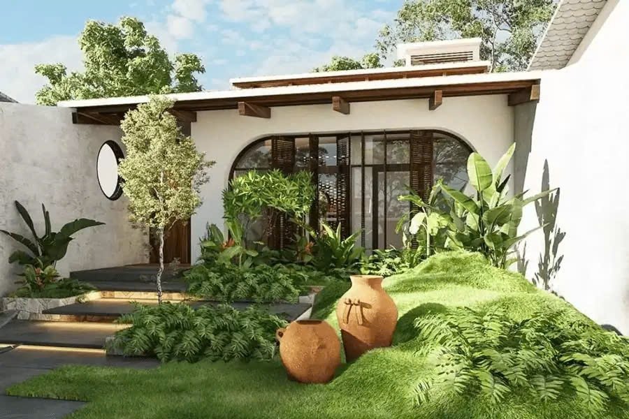 Khu vườn nhiệt đới xanh mướt trước ngôi nhà hiện đại với cây cảnh và chum đất.