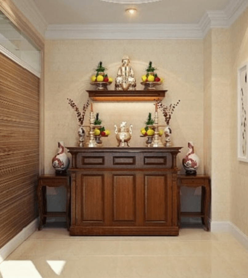 Không gian thờ cúng trang trọng với bàn thờ gỗ, bình hoa và tượng Phật, bố trí hoa quả và đèn trang trí.