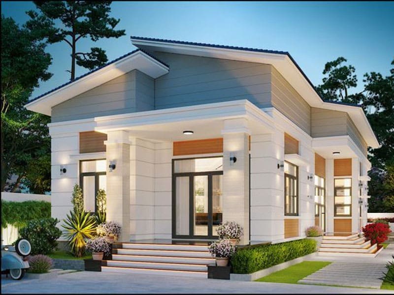 Nhà một tầng hiện đại với mái chéo, cửa kính lớn, xung quanh cây xanh và sân vườn.