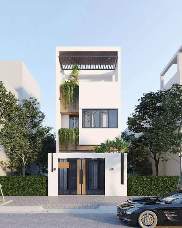 Nhà phố hiện đại ba tầng màu trắng, có cây xanh trang trí và xe hơi đậu trước nhà.