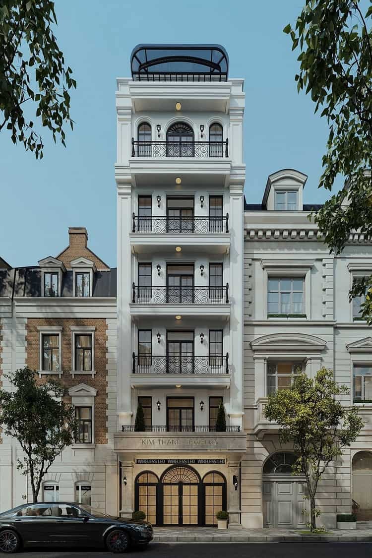 Tòa nhà cổ điển trắng với cửa sổ lớn và ban công, thiên nhiên xanh xung quanh.