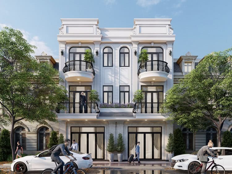 Tòa nhà ba tầng kiến trúc tân cổ điển với ban công đẹp, cây xanh hai bên, và người đi xe đạp phía trước.