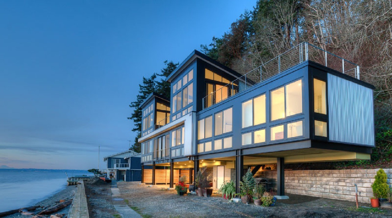 Nhà hiện đại bên bờ biển với cửa kính lớn tại công trình kiến trúc độc đáo, ánh sáng ban đêm lung linh.