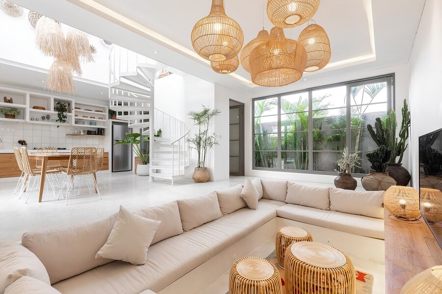 Phòng khách hiện đại với sofa chữ L, bàn mây, đèn trần độc đáo và cầu thang xoắn trắng.