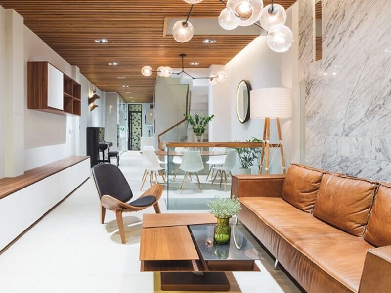 Phòng khách hiện đại với sofa da nâu, bàn gỗ và đèn trang trí sang trọng, nội thất tối giản.