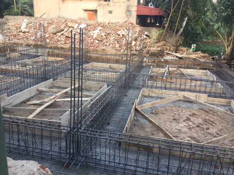 Xây dựng móng nhà với cốt thép và khuôn gỗ, tiến độ công trình đang thi công tại công trường ngoài trời.