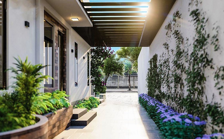 nhung-luu-y-khi-thiet-ke-loi-di-ben-hong-nha-5 Lối đi nhỏ với cây xanh và hoa tím, ánh sáng tự nhiên chiếu qua mái hiên hiện đại.