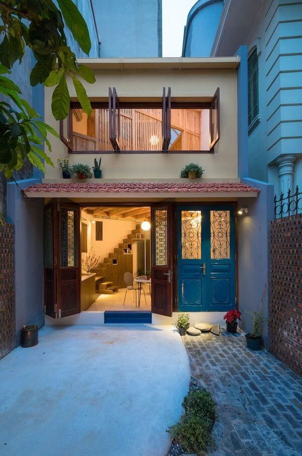 Mặt tiền nhà phố nhỏ, thiết kế hiện đại với cửa sổ gỗ mở, cửa ra vào xanh dương, cây cảnh trang trí.