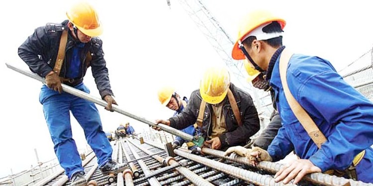 Công nhân đội mũ bảo hộ đang thi công trên công trường xây dựng, gia cố thép cho nền móng tòa nhà.