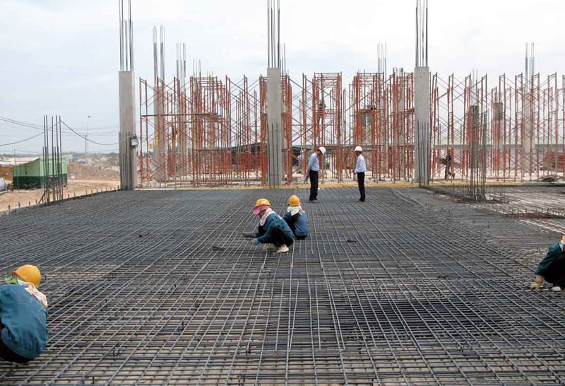 Công nhân xây dựng làm việc trên công trường với giàn giáo và cốt thép.