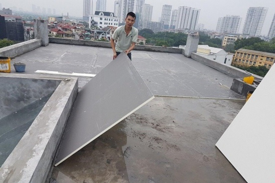 nhuoc-diem-gach-mat Người đàn ông lắp đặt tấm panel cách nhiệt trên tầng thượng tòa nhà đô thị hiện đại.