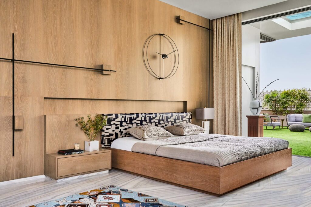 Phòng ngủ hiện đại với giường gỗ, thảm trải sàn và cửa sổ lớn mở ra sân vườn xanh ngoài trời.