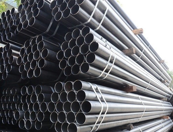 Ống thép được xếp chồng lên nhau ngoài trời, thích hợp cho ngành công nghiệp và xây dựng.