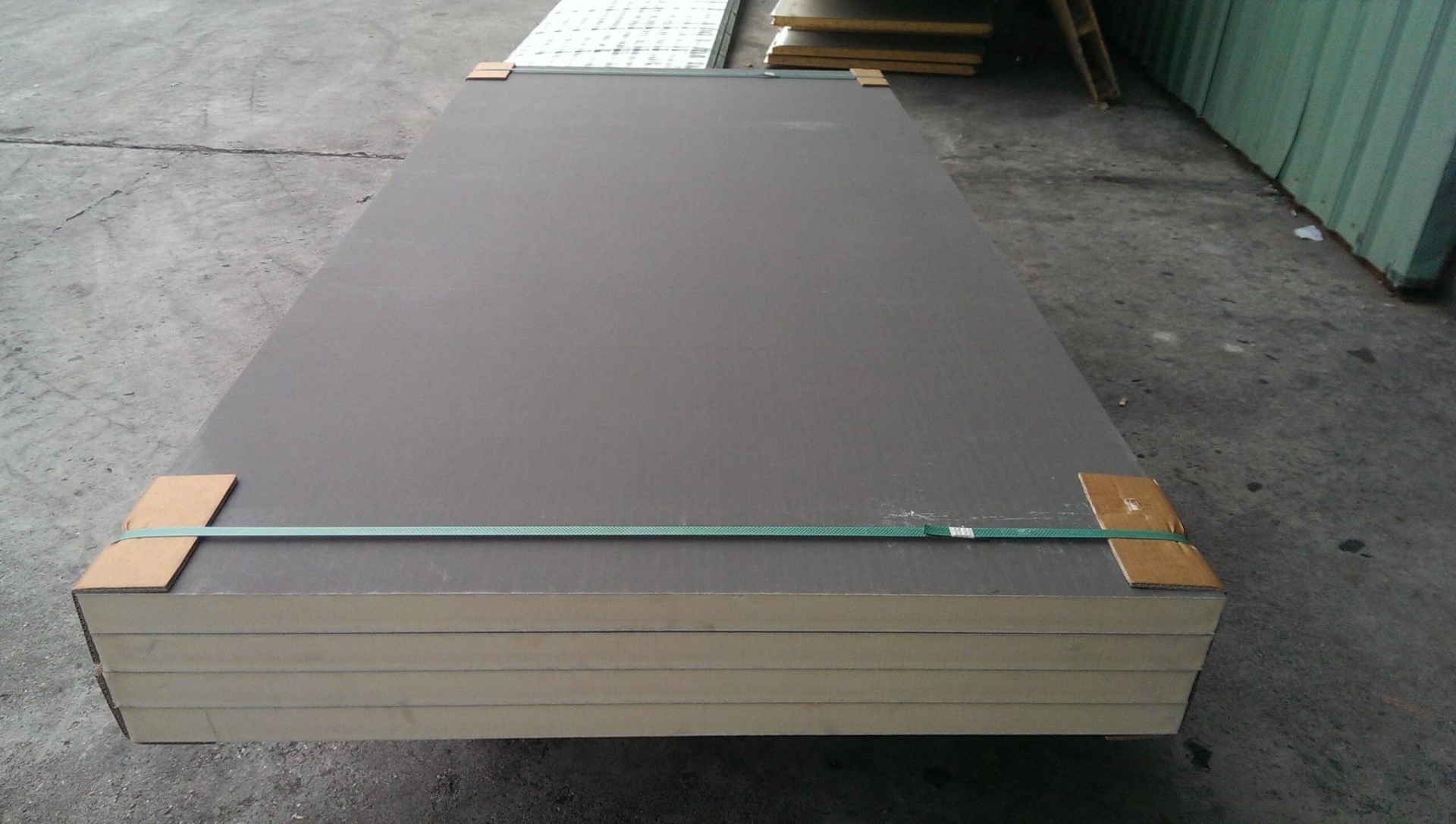 p40sqbmawtuk1lx6oivj Tấm panel cách nhiệt màu xám xếp chồng, sử dụng trong xây dựng, đặt trên nền xi măng trong kho.