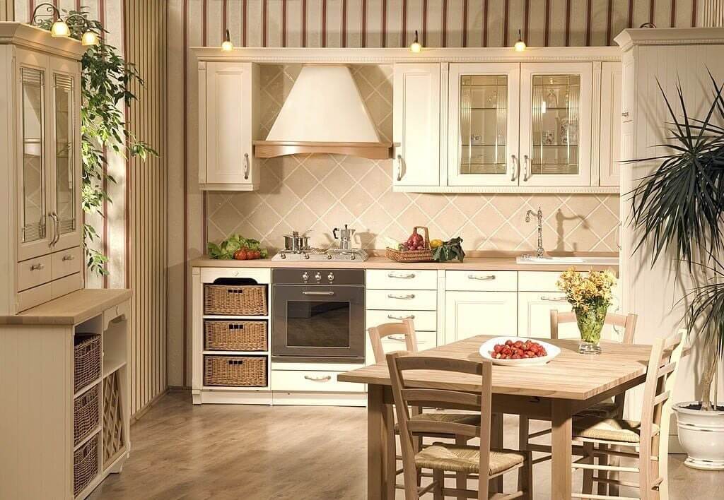 Nhà bếp hiện đại với nội thất gỗ sáng màu, bàn ăn nhỏ và chi tiết trang trí xanh.