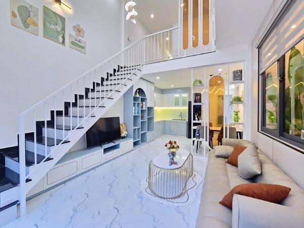 pcrsh79iy6tw1x4z8d5n Phòng khách hiện đại với cầu thang trắng, sofa, bàn trà và kệ TV, thiết kế nội thất tối giản và sáng sủa.