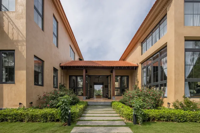 phap-bac-bo Lối vào nhà phong cách cổ điển với cây cỏ xanh và mái ngói đỏ dưới bầu trời trong xanh.