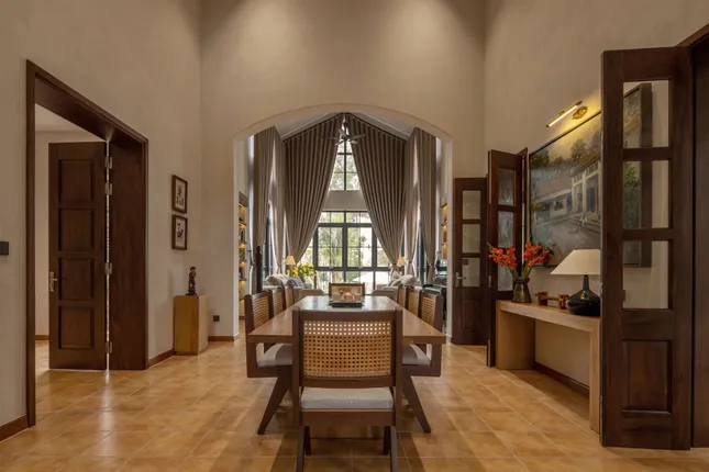 phap-bb-2 Phòng ăn sang trọng với bàn gỗ, ghế mây tre, và đèn trang trí, cửa sổ lớn đón ánh sáng tự nhiên.