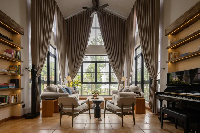 phap-bb-3 Phòng khách sang trọng với cửa kính lớn, rèm dài và đàn piano, thiết kế nội thất hiện đại tạo không gian ấm cúng.