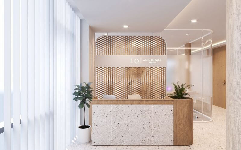 Quầy lễ tân hiện đại với tấm vách chắn họa tiết gỗ và cây xanh, tạo không gian sáng sủa và thoáng đãng.