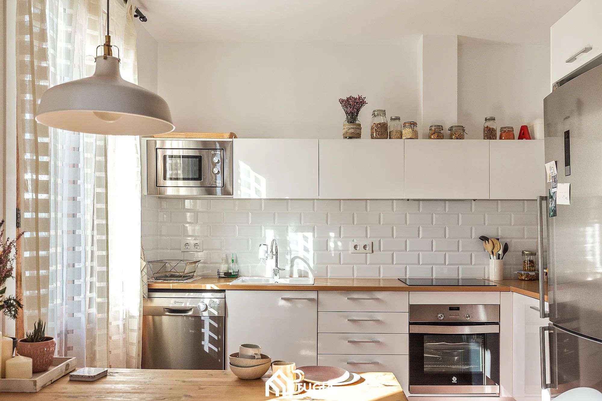 phong-bep-nha-ong-4m-kien-truc-noi-that-tu-gia-21 Nhà bếp hiện đại với tường gạch men trắng, tủ gỗ, lò vi sóng, lò nướng, ánh sáng tự nhiên xuyên qua rèm cửa.