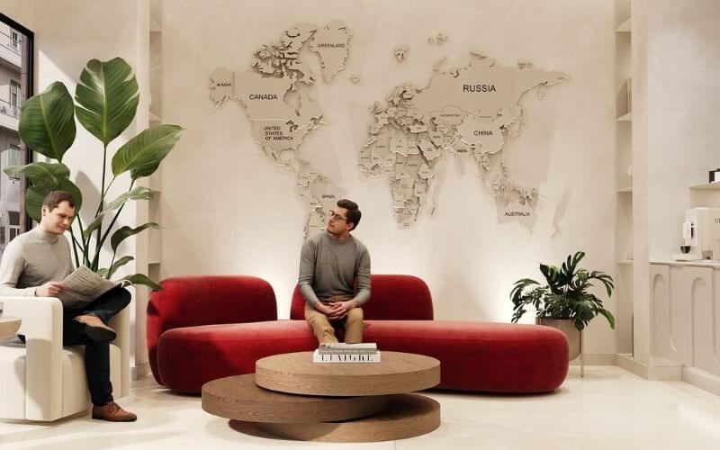 Hai người đàn ông trò chuyện trong phòng khách hiện đại với bản đồ thế giới trên tường và cây xanh trang trí.