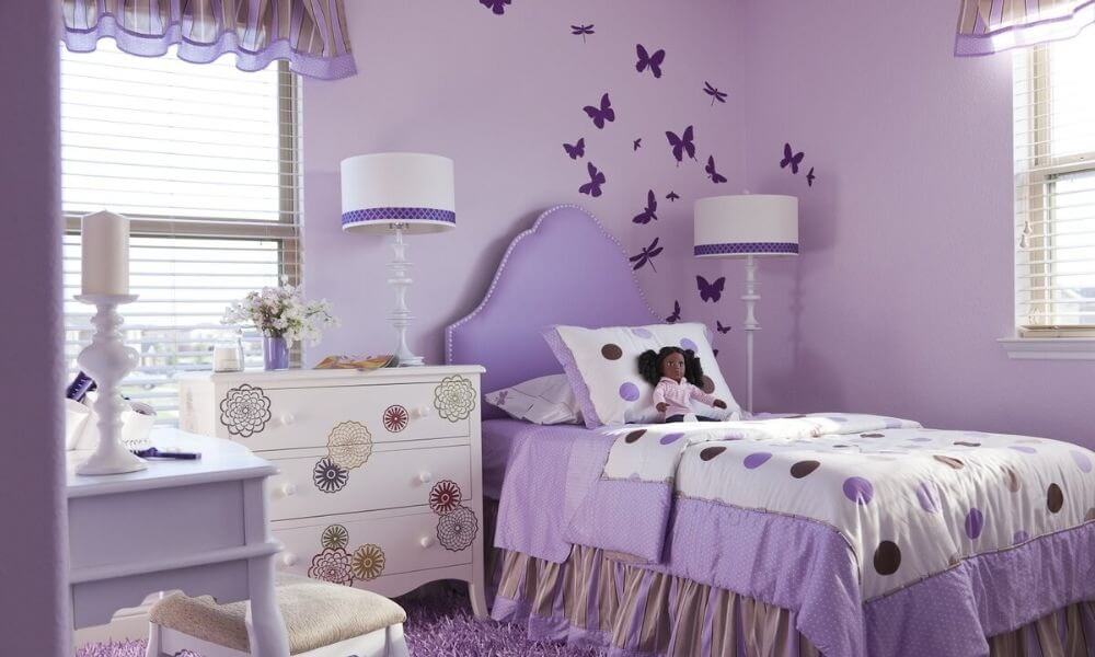 Phòng ngủ trẻ em màu tím mộng mơ với trang trí bướm trên tường và ga giường chấm bi.