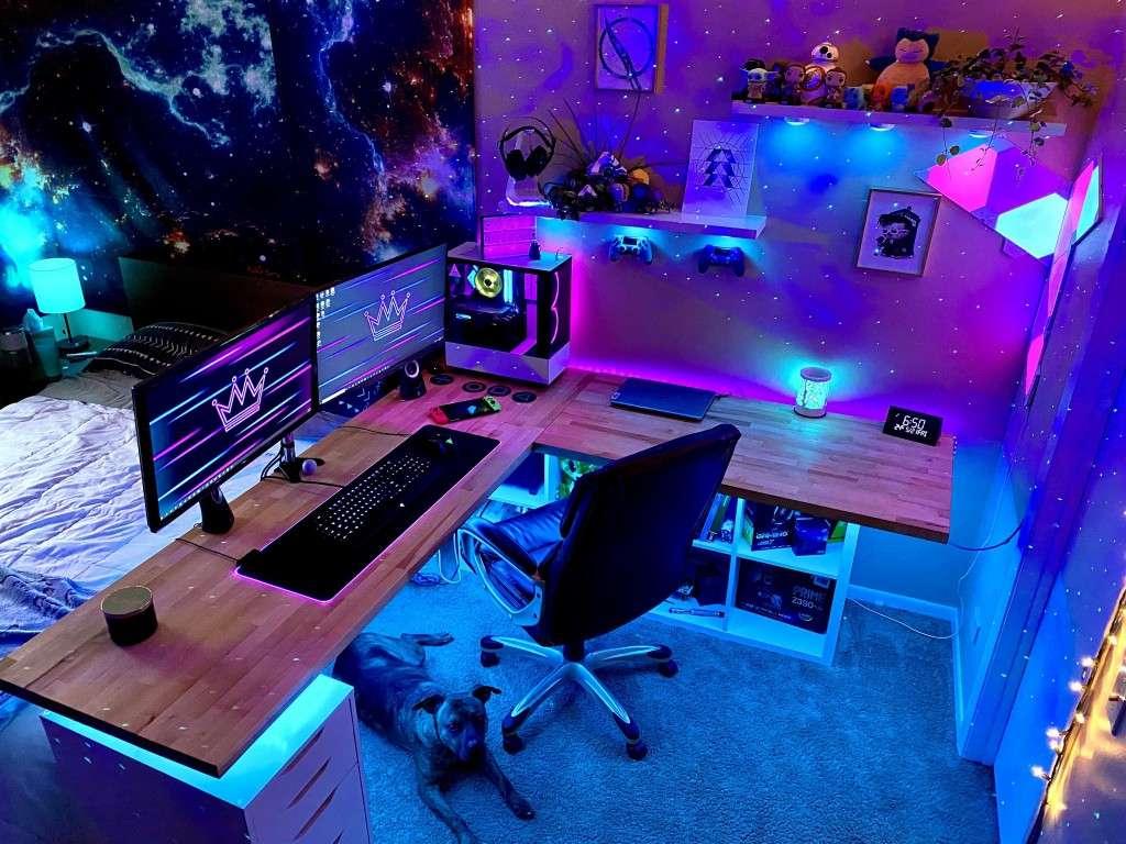 Góc làm việc tiên phong với đèn LED đa màu sắc, hai màn hình, và máy tính RGB trong phòng ngủ trang trí theo phong cách vũ trụ.