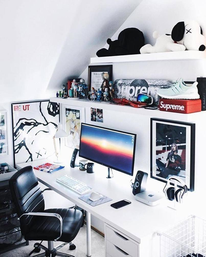 Nơi làm việc hiện đại với máy tính, loa, bàn phím, và ghế xoay da đen, được trang trí bằng tranh và thú nhồi bông.