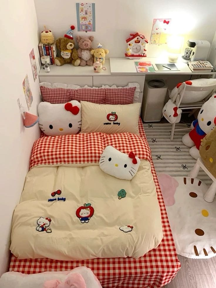 Phòng ngủ trẻ em trang trí Hello Kitty dễ thương, giường trải ga ca rô đỏ trắng và gấu bông trên kệ.
