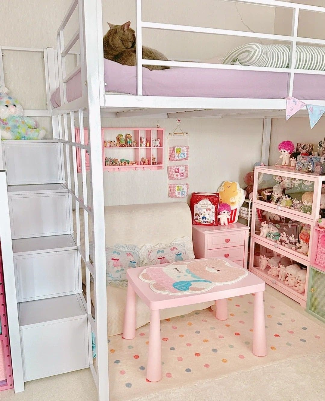 Phòng ngủ gác xép dễ thương với bàn hồng, giường tầng, mèo ngủ trên giường, nhiều đồ chơi trang trí.