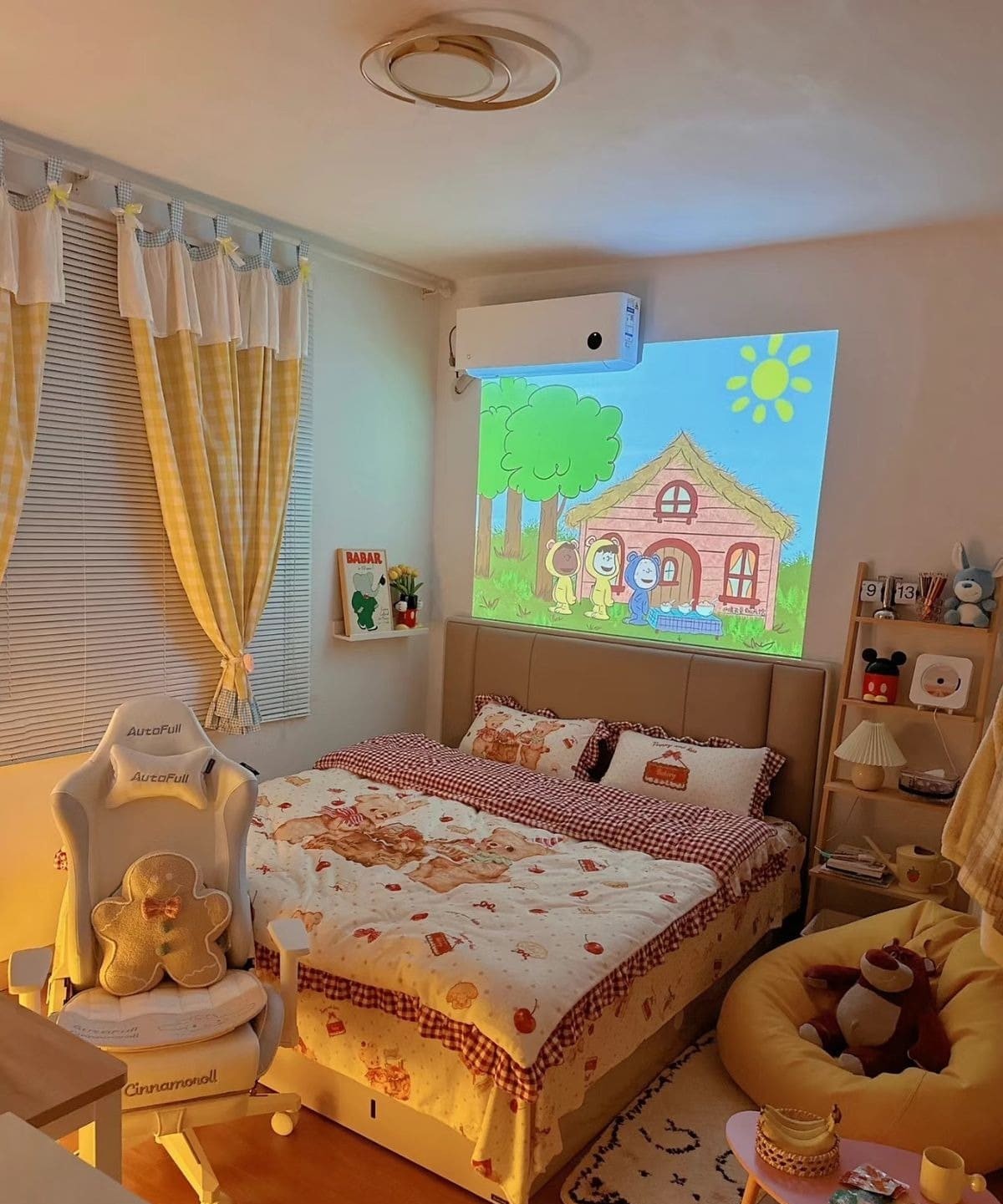 Phòng ngủ ấm cúng với màn hình máy chiếu hoạt hình, nội thất dễ thương và giường trải chăn họa tiết.