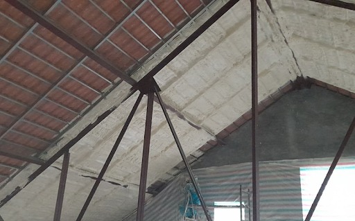 Mái nhà với kết cấu khung thép và tấm lợp, có lớp cách nhiệt màu trắng và cửa sổ ánh sáng tự nhiên.