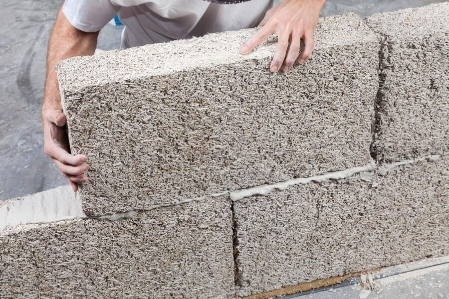 Người thợ xây đang đặt viên gạch Hempcrete vào tường, sử dụng vật liệu xây dựng bền vững và thân thiện môi trường.