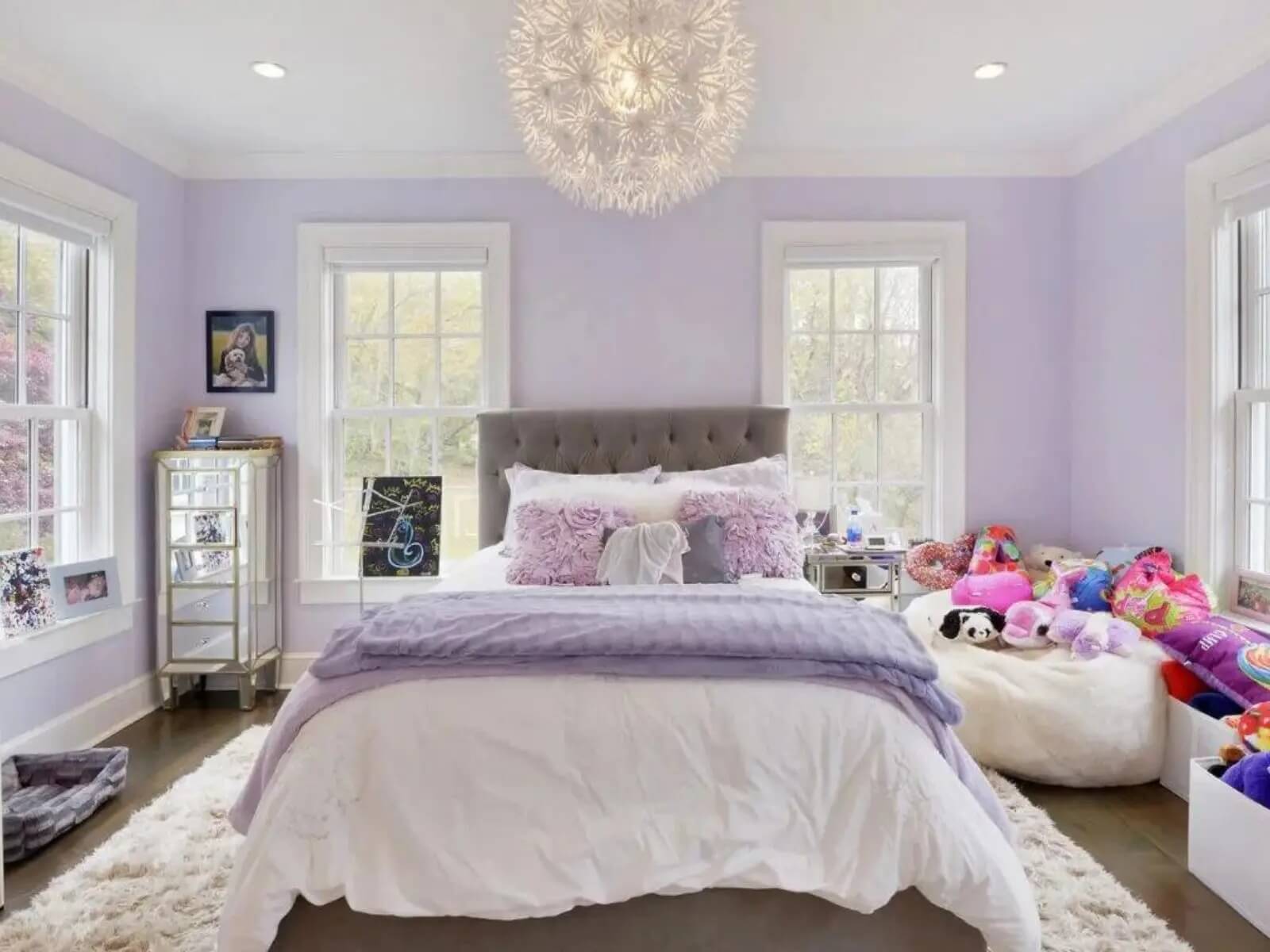 Phòng ngủ màu tím nhạt với giường êm, đèn trần đẹp và gối trang trí.