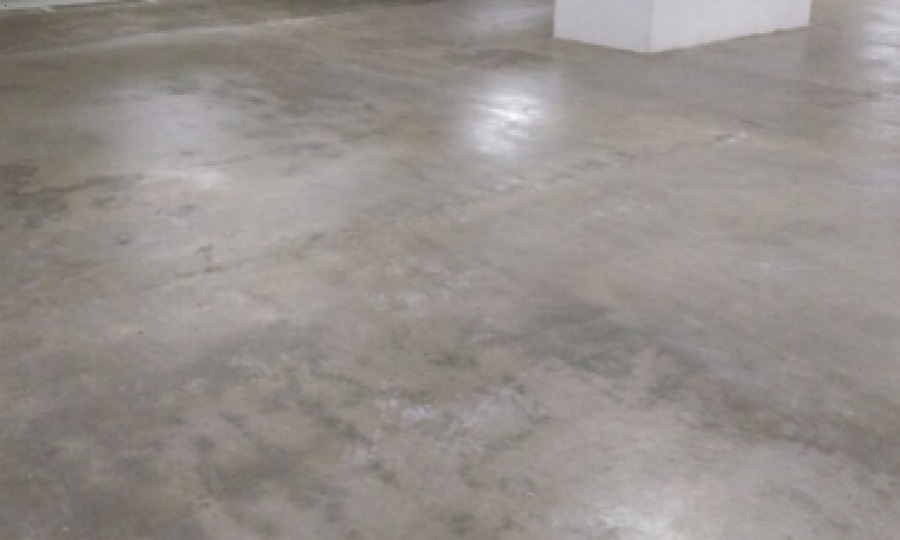 Sàn bê tông trống, màu xám, phản chiếu ánh sáng trong không gian nội thất rộng lớn.