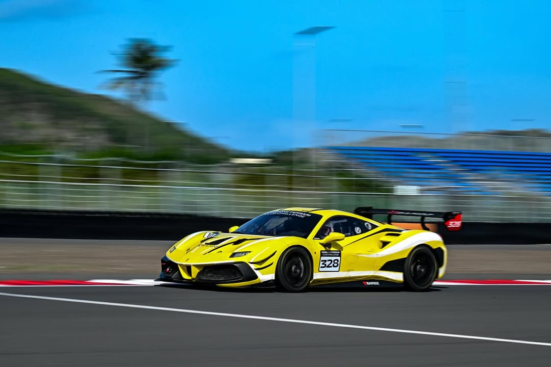 saveinsta-to_504209348_18390136045139061_8411987858488197293_n Xe đua màu vàng chạy nhanh trên đường đua với phong cảnh nền xanh mát.