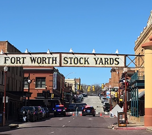 screenshot-2025-07-17-163326 Cổng vào khu Fort Worth Stockyards, Texas, với khung cảnh đường phố nhộn nhịp và xe cộ qua lại.