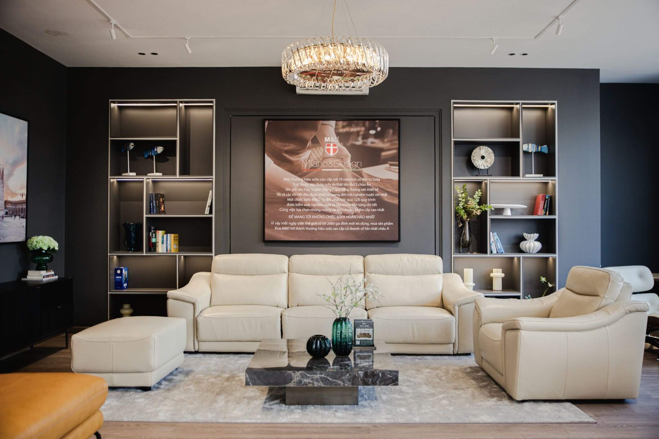 Phòng khách sang trọng với sofa da trắng, bàn đá đen, kệ sách và đèn chùm hiện đại.