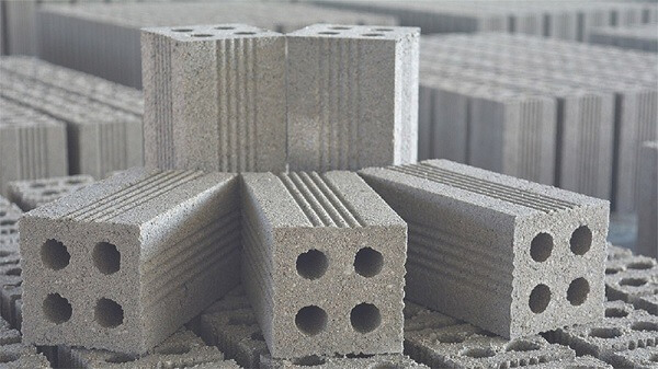 Các viên gạch bê tông xếp chồng với lỗ tròn, dùng trong xây dựng.